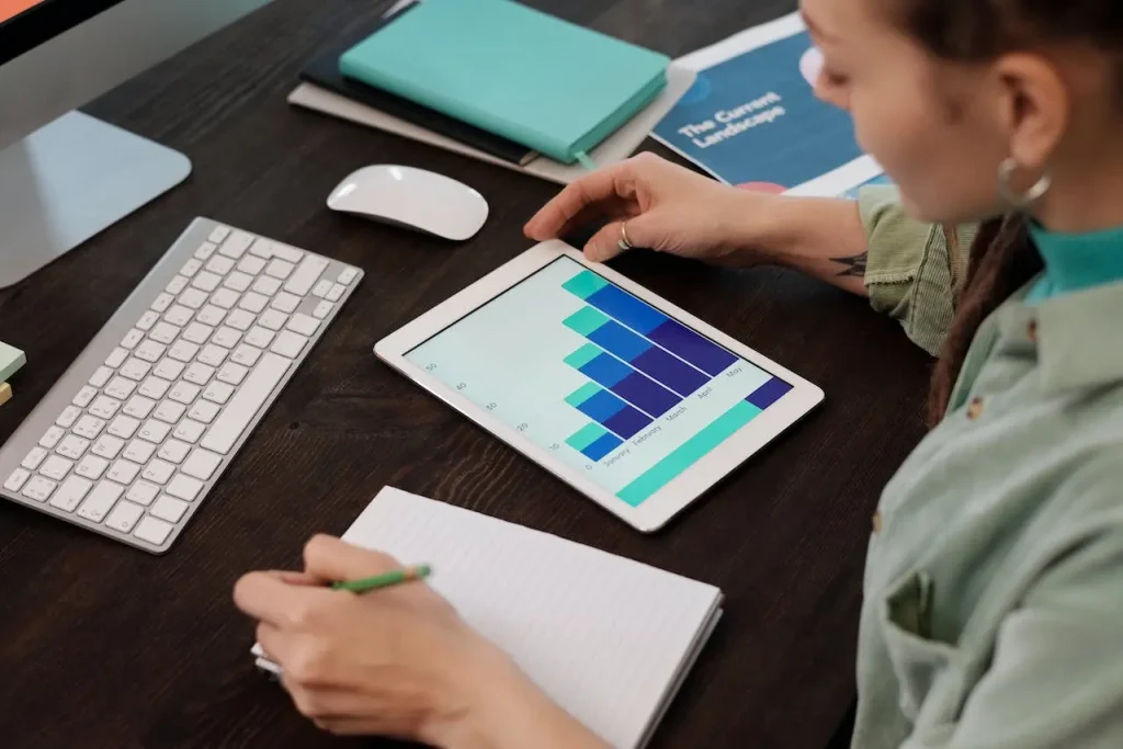 A woman recording financial graph data from tablet, representing accounting outsourcing services.